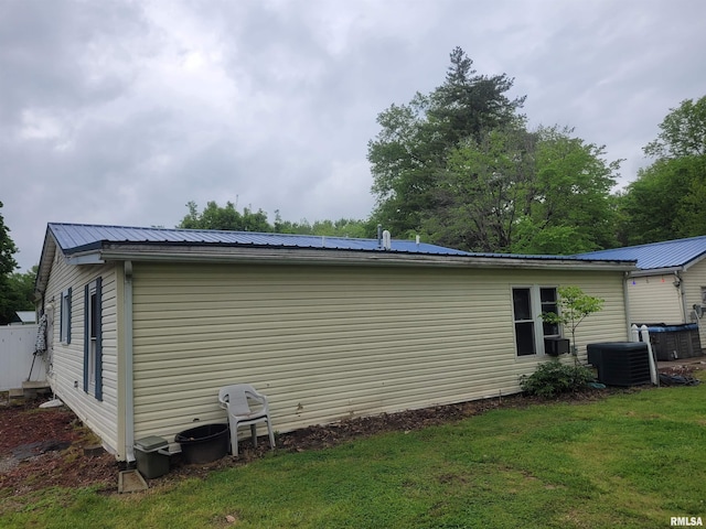 view of side of home featuring a lawn, metal roof, and cooling unit