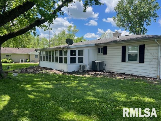 back of property with a yard, a chimney, and central AC