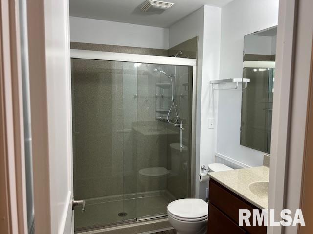bathroom with vanity, toilet, a shower stall, and visible vents