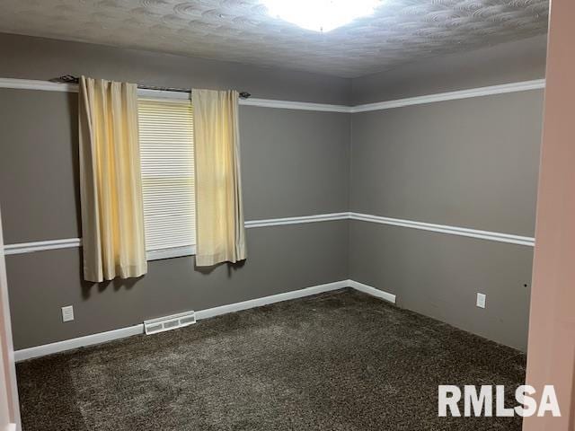 empty room with dark colored carpet, a textured ceiling, and visible vents