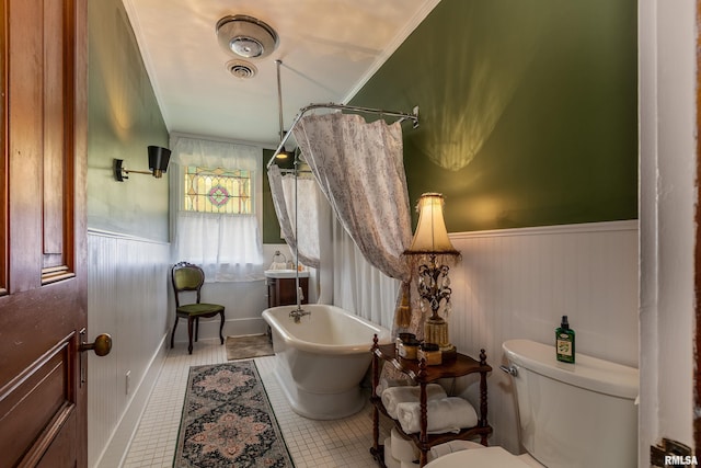 301 W High St, Anna, IL 62906 - bathroom with toilet, a freestanding tub, a wainscoted wall, ornamental molding, and tile patterned floors