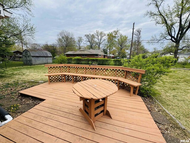 wooden deck featuring a yard, an outdoor structure, and a storage unit