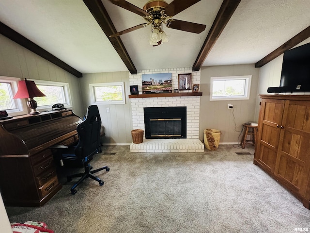 carpeted home office featuring a brick fireplace, beam ceiling, wooden walls, ceiling fan, and baseboards