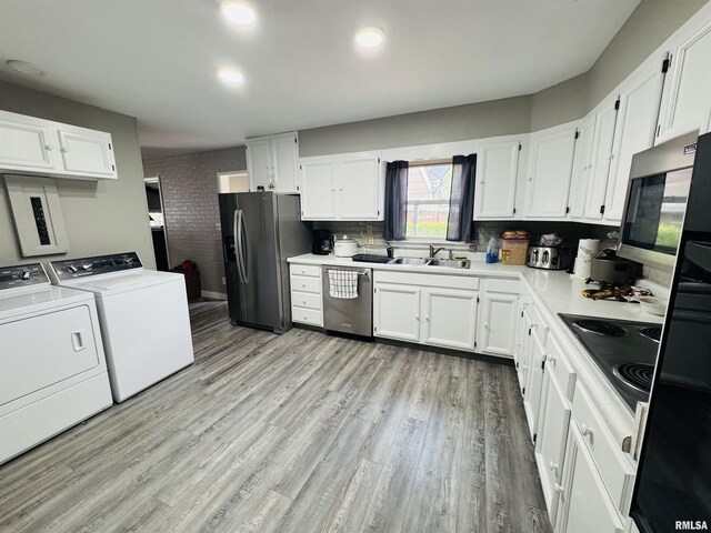 kitchen with stainless steel appliances, washing machine and clothes dryer, white cabinets, and brick wall