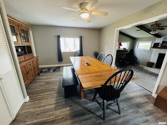 dining area featuring ceiling fan, dark wood-style flooring, plenty of natural light, and brick wall