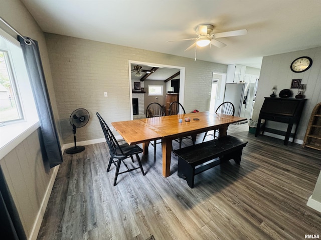 dining room featuring ceiling fan, brick wall, and dark wood-type flooring