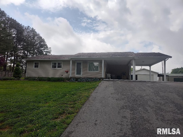 view of front of home with a front yard, an attached carport, an outdoor structure, and driveway