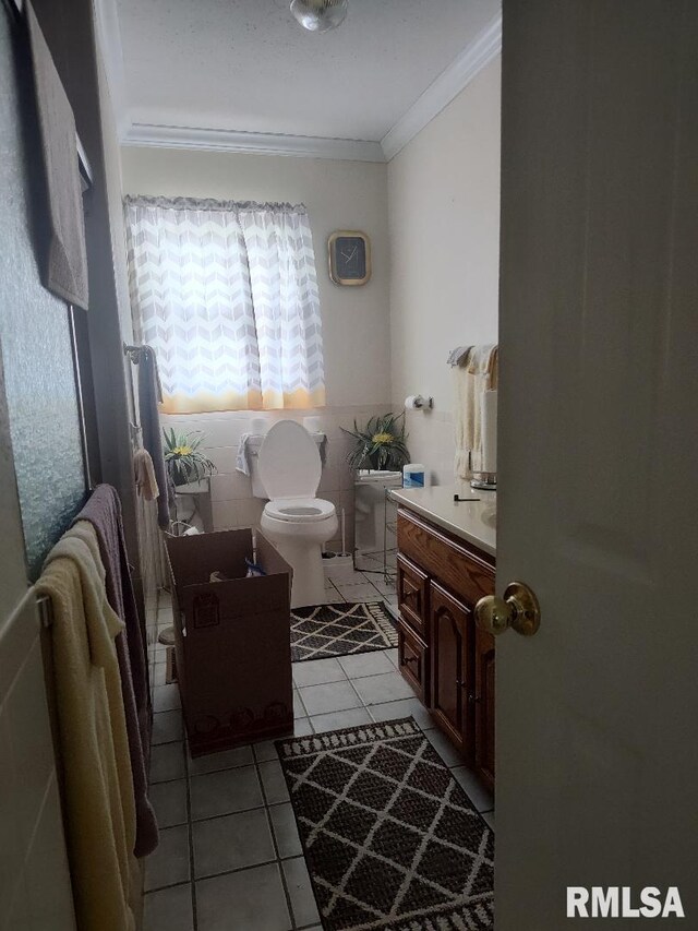 bathroom featuring ornamental molding, toilet, vanity, tile patterned flooring, and tile walls