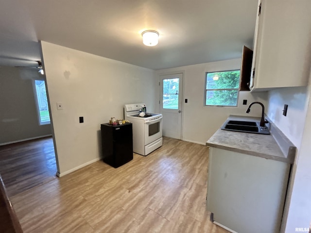 104 W Maple St, Cobden, IL 62920 - kitchen featuring white range with electric cooktop, a sink, light countertops, and light wood-type flooring