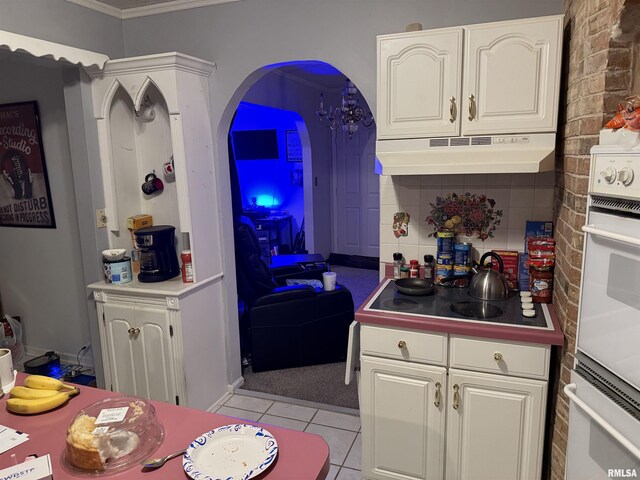 11729 Kevin Ln, Carterville, IL 62918 - kitchen featuring under cabinet range hood, white cabinets, light tile patterned flooring, crown molding, and decorative backsplash