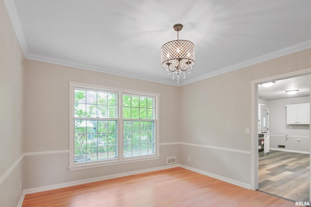 802 W Main St, Vienna, IL 62995 - spare room with ornamental molding, light wood-style flooring, a chandelier, and baseboards