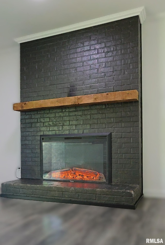 detailed view of a fireplace, crown molding, and wood finished floors