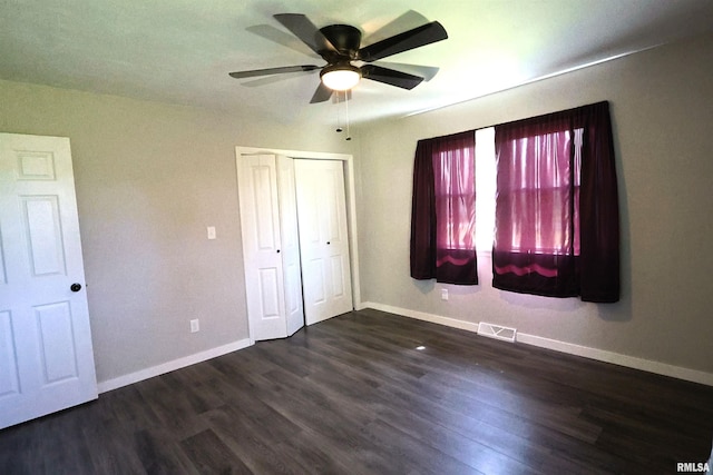 unfurnished bedroom with baseboards, dark wood-type flooring, a closet, and ceiling fan