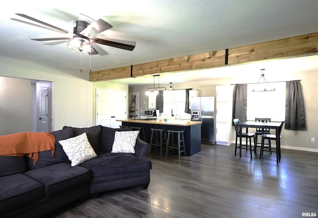living room featuring dark wood-style flooring, a ceiling fan, beam ceiling, and baseboards