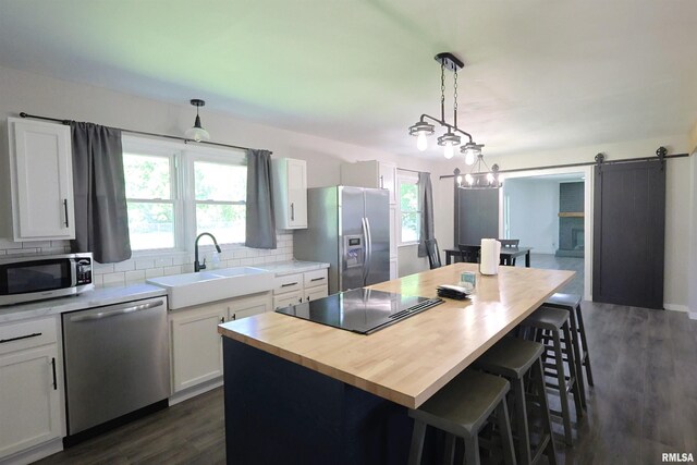 kitchen featuring appliances with stainless steel finishes, a sink, a breakfast bar, tasteful backsplash, and wooden counters