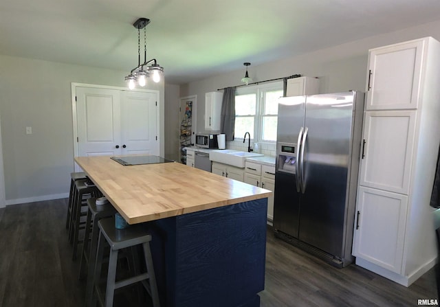 kitchen featuring appliances with stainless steel finishes, a sink, butcher block countertops, dark wood-style floors, and white cabinets