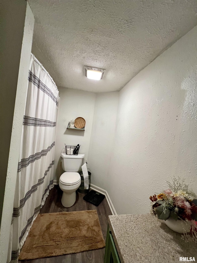 405 E Saint Louis St, West Frankfort, IL 62896 - bathroom featuring wood finished floors, toilet, a textured ceiling, baseboards, and a shower with shower curtain