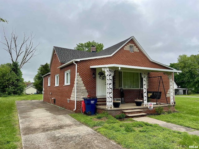405 E Saint Louis St, West Frankfort, IL 62896 - bungalow featuring covered porch, a chimney, a front lawn, roof with shingles, and brick siding