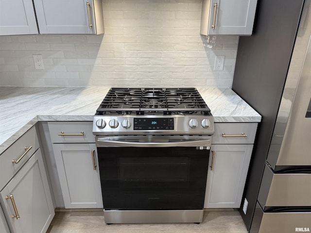 920 E 3rd St, Centralia, IL 62801 - kitchen with appliances with stainless steel finishes, tasteful backsplash, gray cabinets, and light wood-type flooring