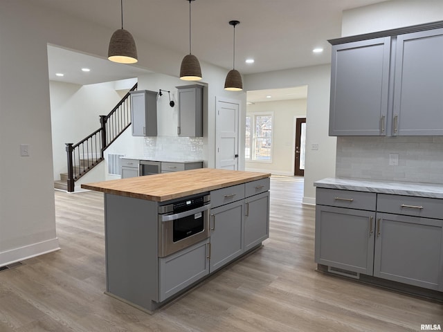 920 E 3rd St, Centralia, IL 62801 - kitchen with gray cabinetry, butcher block countertops, light wood finished floors, backsplash, and baseboards