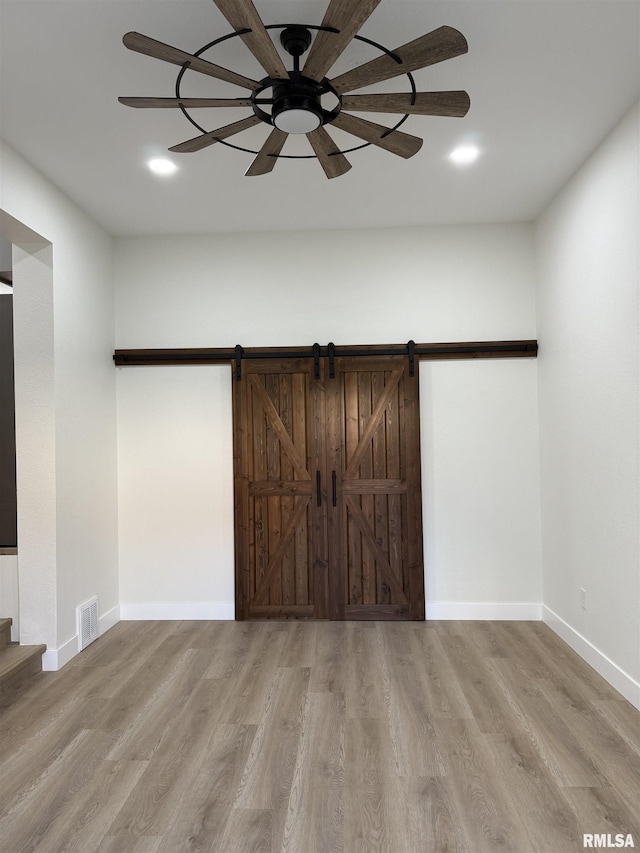 920 E 3rd St, Centralia, IL 62801 - unfurnished bedroom with wood finished floors, baseboards, a ceiling fan, and a barn door