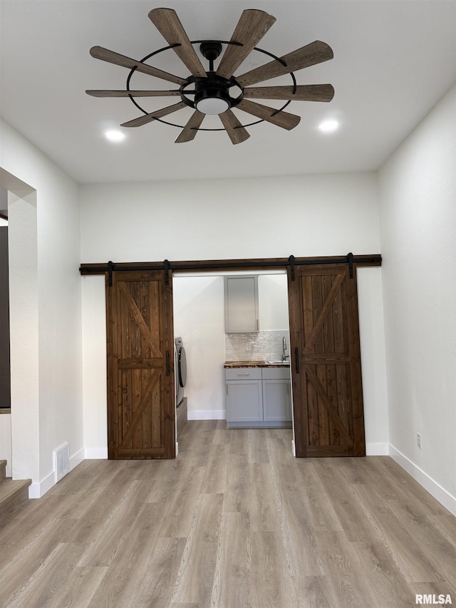 920 E 3rd St, Centralia, IL 62801 - unfurnished living room featuring a barn door, light wood-type flooring, and baseboards