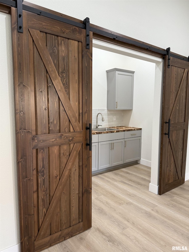 920 E 3rd St, Centralia, IL 62801 - bar area with a barn door, a sink, light wood-type flooring, tasteful backsplash, and baseboards