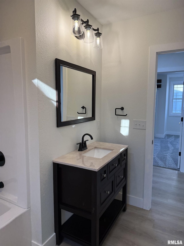 920 E 3rd St, Centralia, IL 62801 - bathroom with wood finished floors, baseboards, vanity, and a tub to relax in
