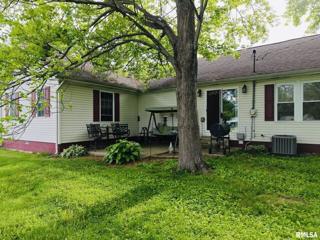 105 E Yung St, Sesser, IL 62884 - rear view of house with a patio area, cooling unit, a lawn, and a shingled roof