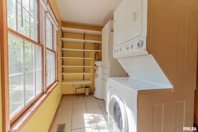 15751 E Tolle Rd, Mount Vernon, IL 62864 - laundry room featuring stacked washer and clothes dryer, electric water heater, light tile patterned floors, and baseboards