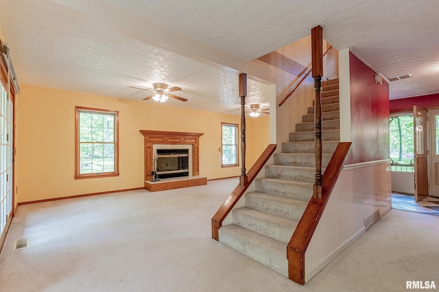 15751 E Tolle Rd, Mount Vernon, IL 62864 - staircase with a textured ceiling, carpet flooring, a ceiling fan, a glass covered fireplace, and baseboards
