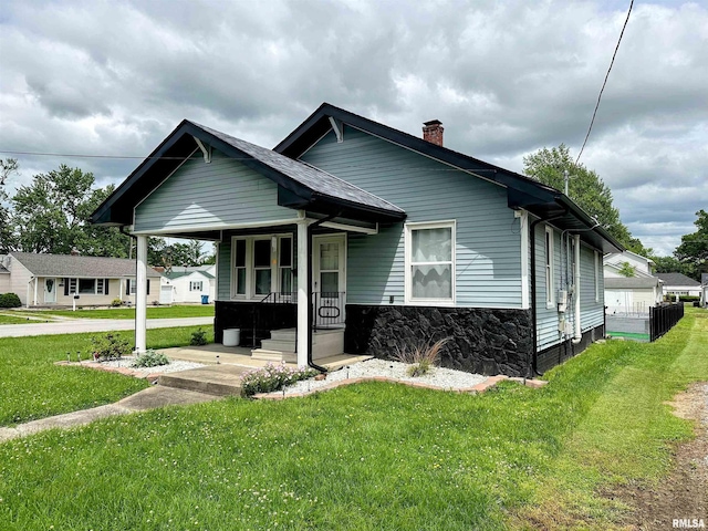 401 S 1st St, Marion, IL 62959 - view of front facade featuring covered porch, a chimney, a front yard, and stone siding