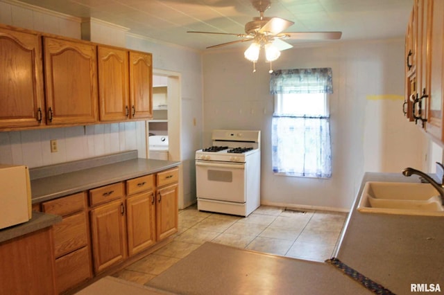207 Butler St, Metropolis, IL 62960 - kitchen featuring white gas range oven, a sink, a ceiling fan, light tile patterned floors, and brown cabinetry