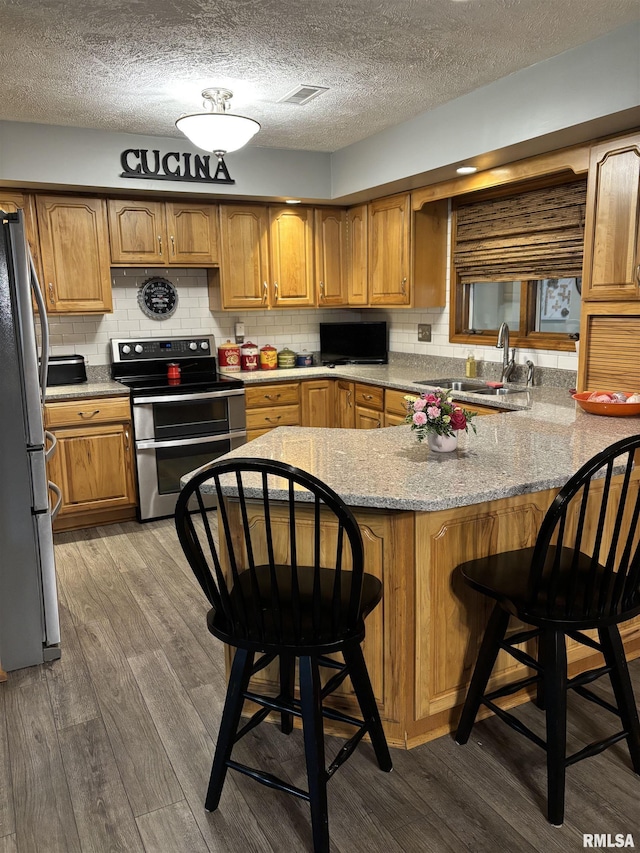 13916 Leisure Ln, Benton, IL 62812 - kitchen with stainless steel appliances, a peninsula, wood finished floors, a textured ceiling, and backsplash