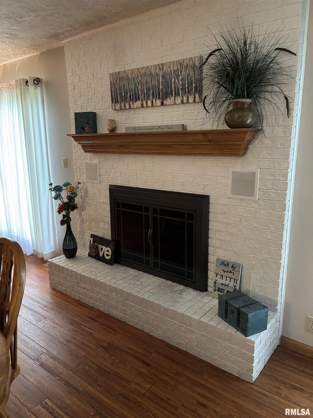 13916 Leisure Ln, Benton, IL 62812 - detailed view of wood finished floors, a brick fireplace, baseboards, and a textured ceiling