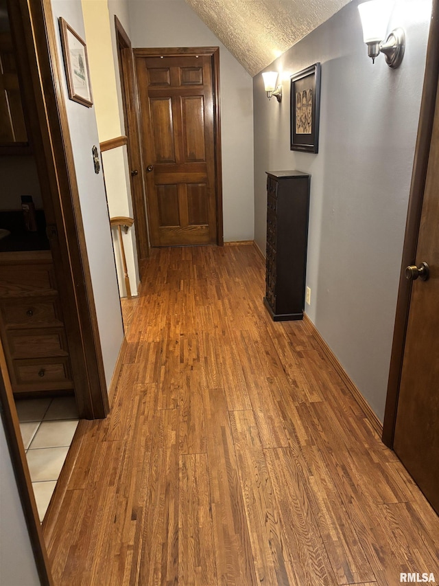 13916 Leisure Ln, Benton, IL 62812 - hall featuring vaulted ceiling, wood finished floors, a textured ceiling, and baseboards