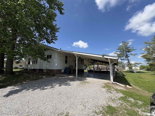 manufactured / mobile home with gravel driveway, a front lawn, and an attached carport
