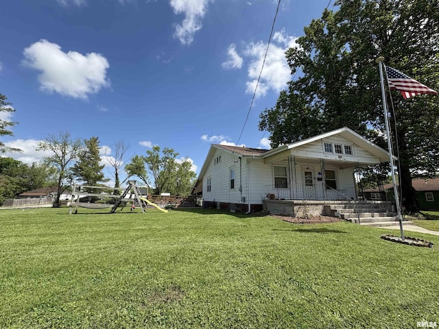view of home's exterior with covered porch, a playground, and a yard