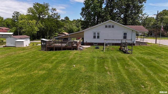 rear view of property with a shed, a deck, an outbuilding, and a lawn