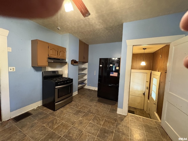 kitchen featuring stainless steel gas stove, freestanding refrigerator, under cabinet range hood, baseboards, and a textured ceiling