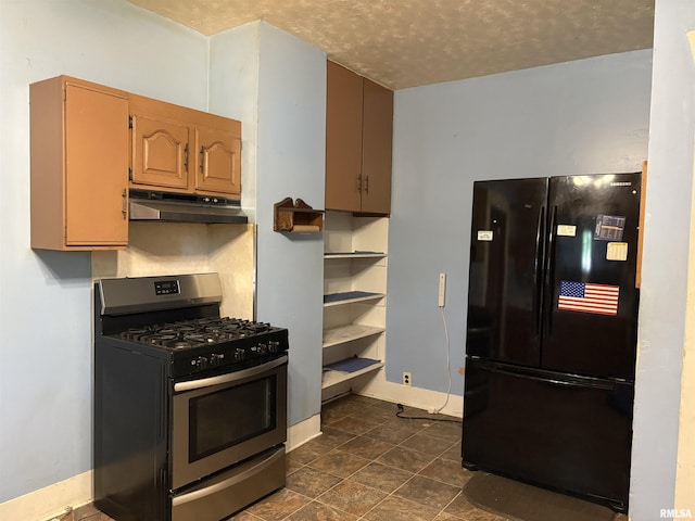 kitchen featuring freestanding refrigerator, stainless steel gas range, under cabinet range hood, baseboards, and a textured ceiling