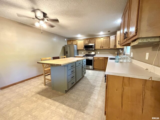 7544 Geranium Rd, Oakdale, IL 62268 - kitchen featuring appliances with stainless steel finishes, a kitchen bar, a textured ceiling, a ceiling fan, and a center island