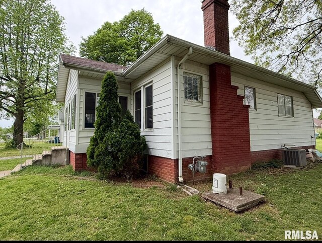 105 E Rea St, Valier, IL 62891 - view of home's exterior with a chimney, central AC unit, and a lawn
