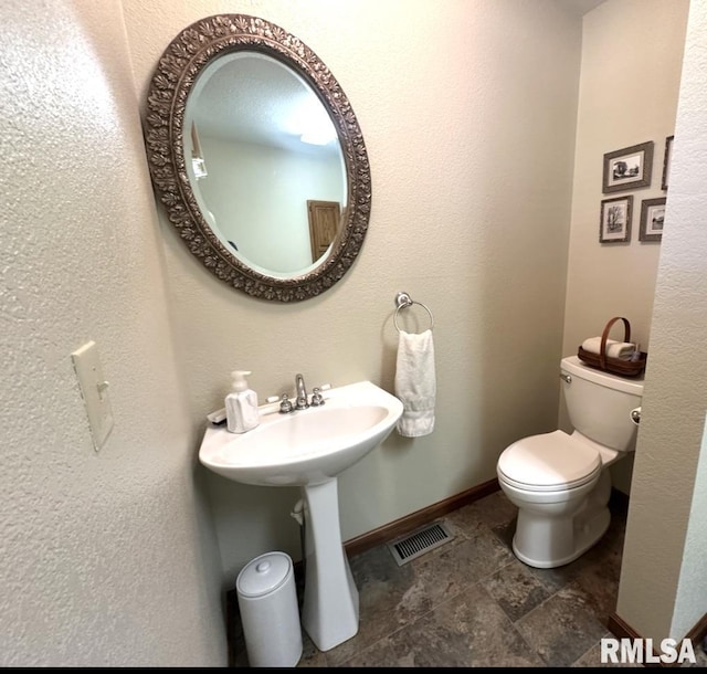 23208 N US Highway 51, Centralia, IL 62801 - bathroom with baseboards, toilet, stone finish flooring, and a sink