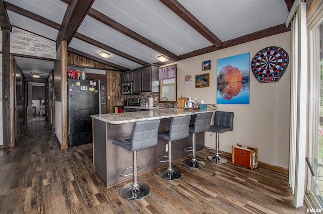 631 Community Beach Rd, Centralia, IL 62801 - kitchen with a peninsula, stainless steel microwave, dark wood-style flooring, freestanding refrigerator, and light stone counters