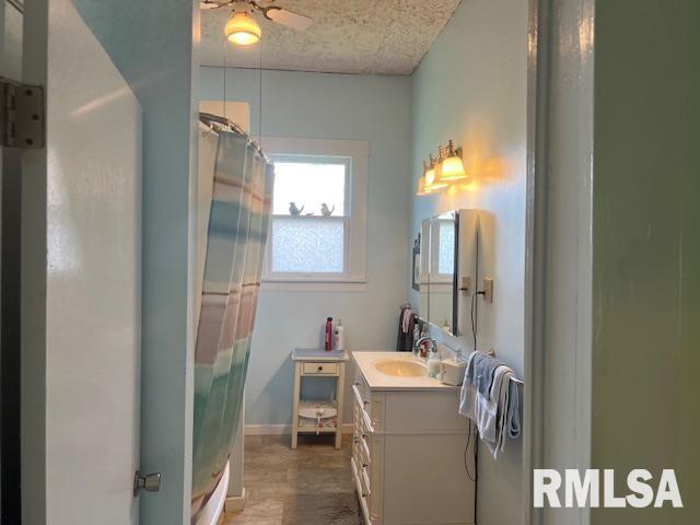full bath with a shower with curtain, vanity, ceiling fan, and baseboards