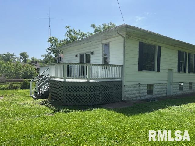 back of property with a yard, a deck, and stairway