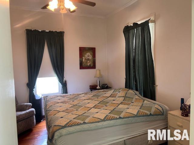 bedroom featuring crown molding, wood finished floors, and a ceiling fan