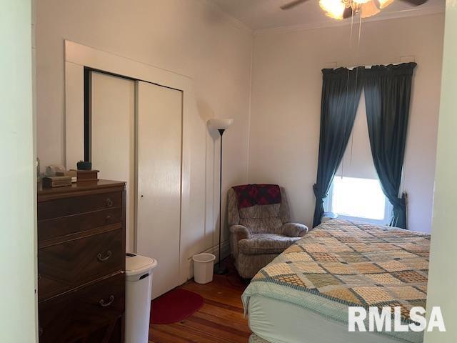 bedroom with wood finished floors, a closet, a ceiling fan, and ornamental molding