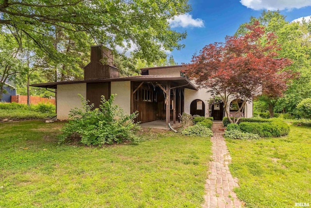 back of property featuring a yard and stucco siding